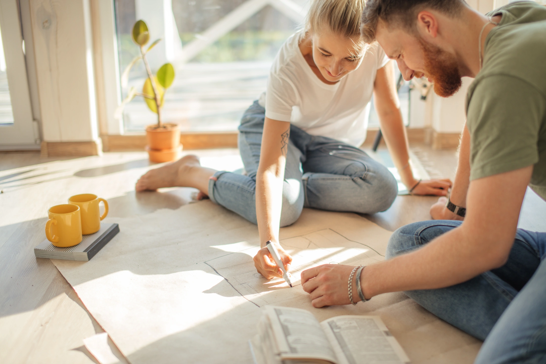 couple planning new home blueprint on living room floor